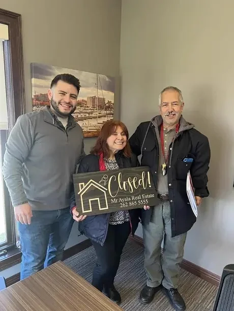 Couple holding the Mr Ayala Real Estate Closed sign
